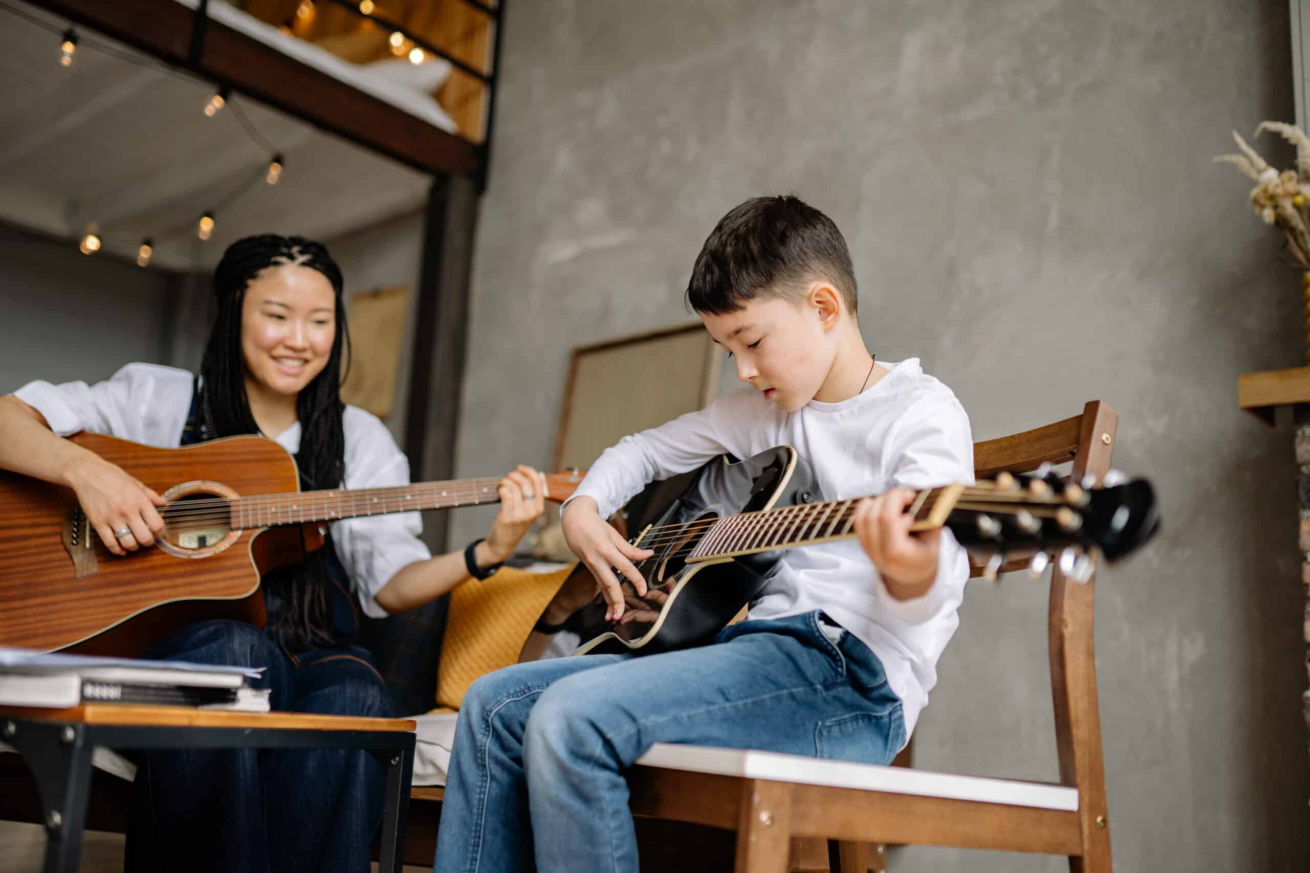 Kid and a woman playing guitars together
